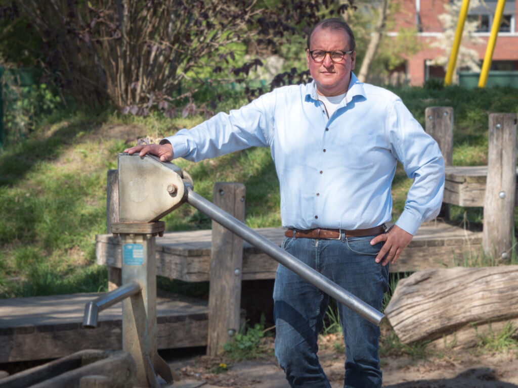 Chris Bouwman in de natuur naast een waterpomp