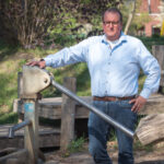 Chris Bouwman in de natuur naast een waterpomp